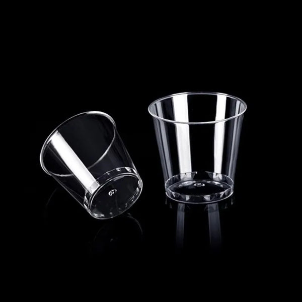 A clear glass shot glass is shown against a black background.