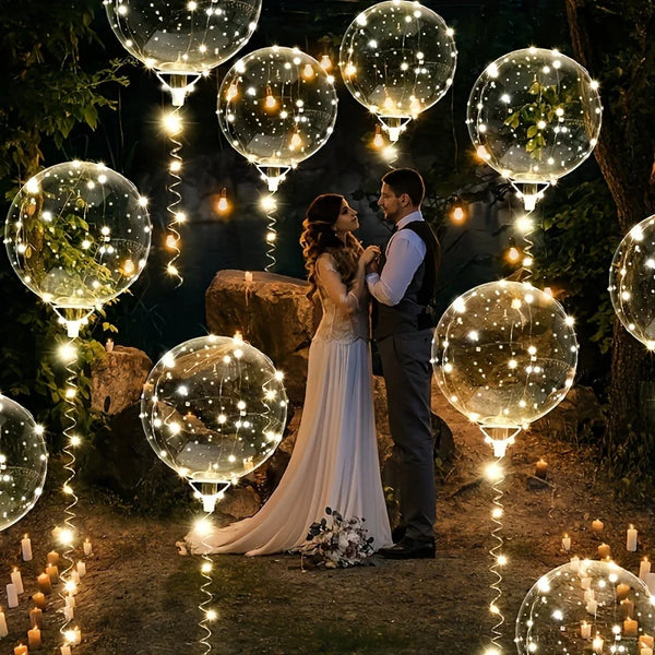 Una pareja está en un entorno exterior tenue rodeada de esferas de globos iluminados LED y luces de cuerda.