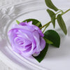 A light purple velvet artificial rose with a green stem rests on a white plate.