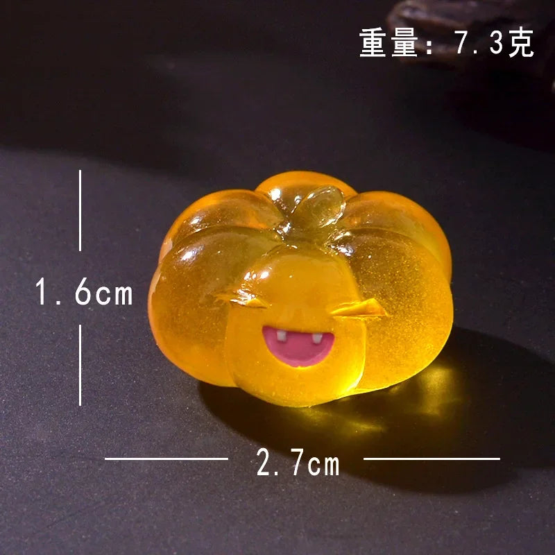 A round, yellow luminous resin ornament shaped like a smiling ghost face, with dimensions 1.6cm by 2.7cm.