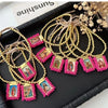 Gold-plated charm bracelets featuring Virgin Mary Guadalupe figures and pink beadwork displayed on a black tray.