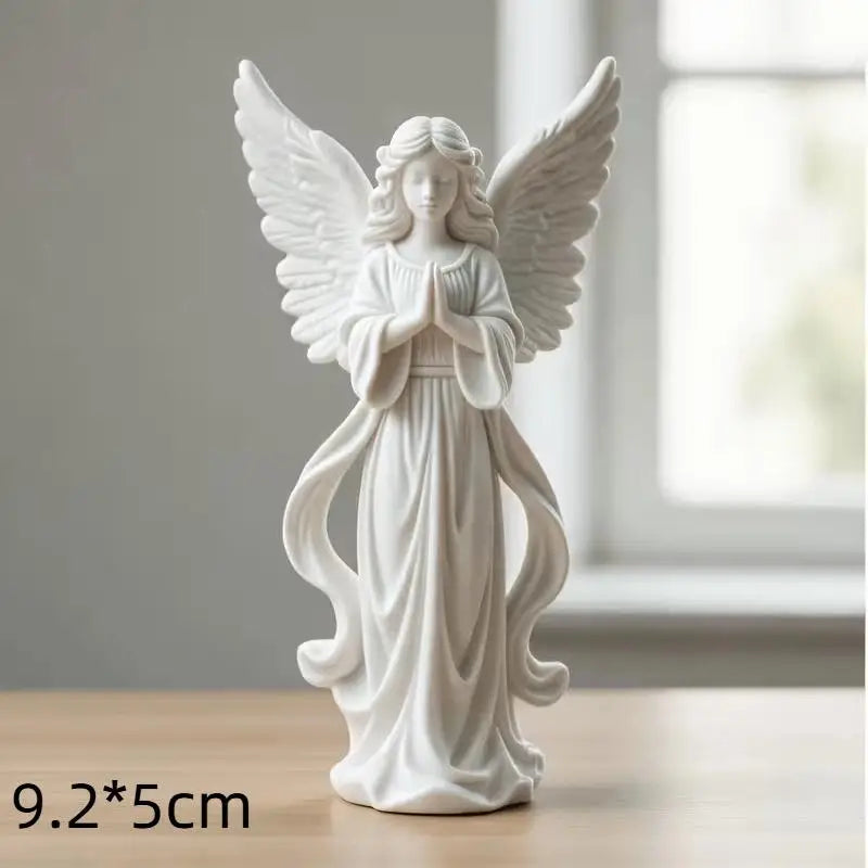 White gold praying angel figurine with outstretched wings and hands, standing on a wooden surface.