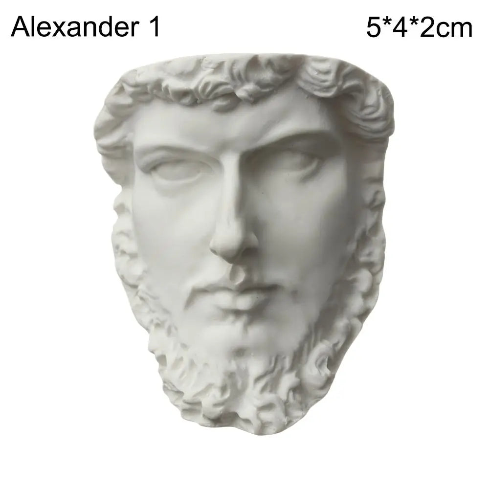 A white plaster bust miniature of a male face with curly hair and a beard.