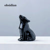 Schwarzes Obsidian-Schnitzwerk eines Wolfes, der auf einer weißen Oberfläche sitzt.