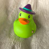 A bright green rubber duck bath toy wearing a purple hat and an orange beak.
