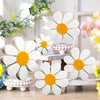 Set of three white and orange wooden daisy flower ornaments displayed on a light wooden surface.
