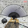An elegant vintage Chinese folding hand fan with gray and black ribs displayed on a wooden stand.