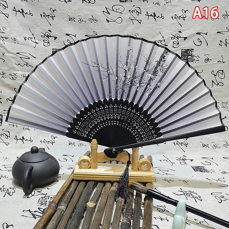 An elegant vintage Chinese folding hand fan with gray and black ribs displayed on a wooden stand.
