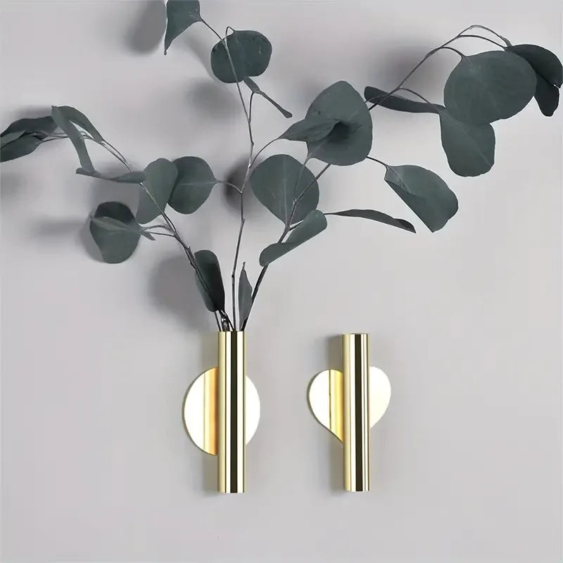 Wandmontierte Blumenvase mit Eukalyptuszweigen und goldenen Akzenten