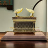 A golden metal statue of the Ark of the Covenant resting on a wooden surface.