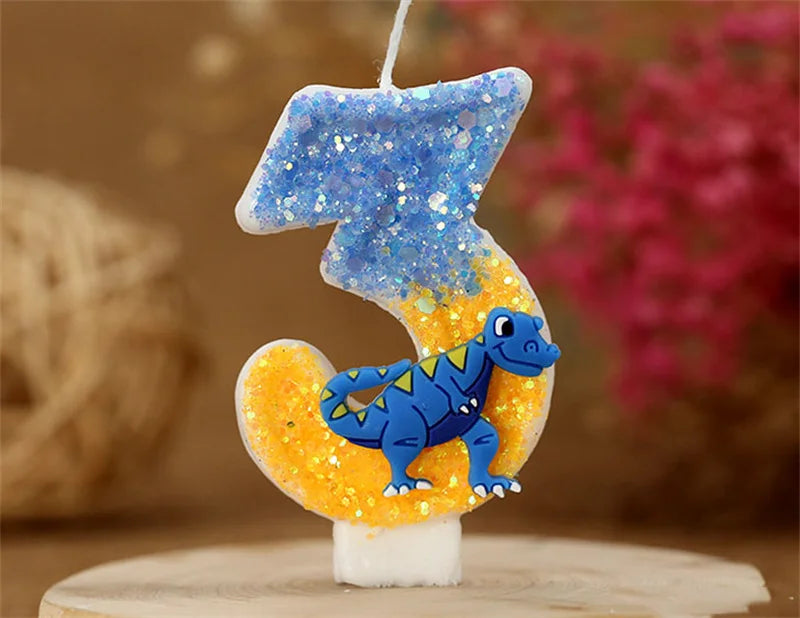 A birthday candle shaped like the number 3, decorated with blue glitter and a yellow dinosaur figure.