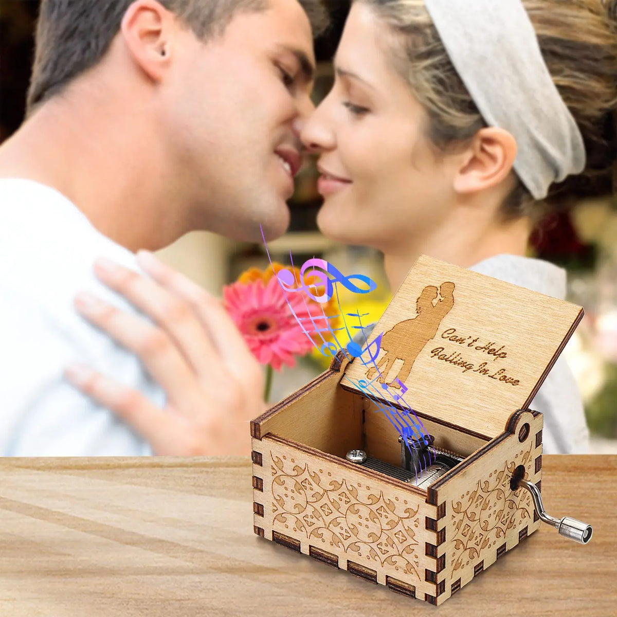 A vintage hand-cranked wooden music box with a lid open, featuring a silhouette of a couple and musical notes.