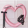 Pink heart-shaped balloon decoration with Happy Birthday text and a black ribbon.