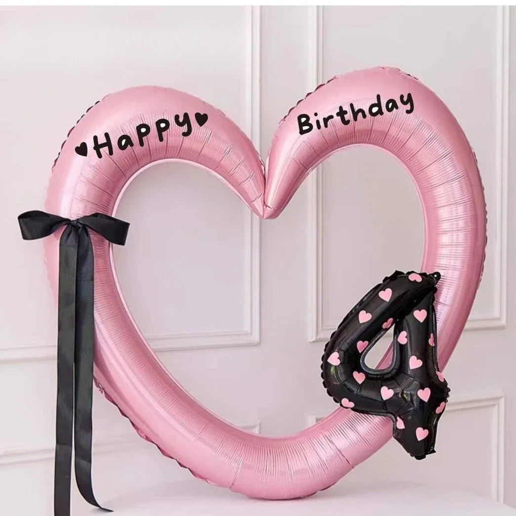 Pink heart-shaped balloon decoration with Happy Birthday text and a black ribbon.