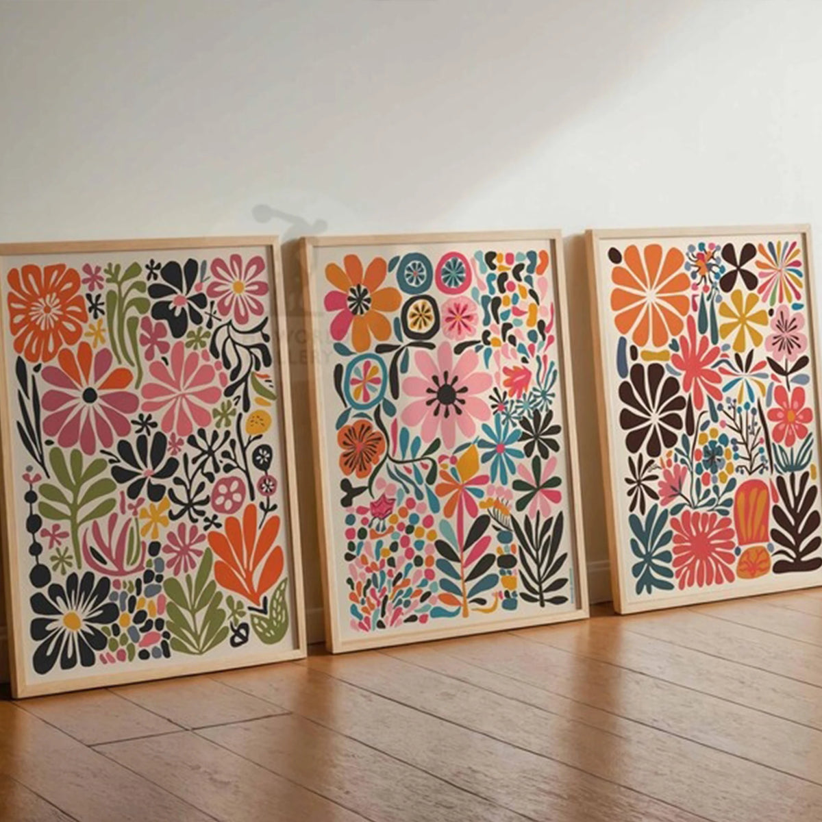 Un juego de tres impresiones florales botánicas enmarcadas con flores y follaje colorido en marcos de madera clara.