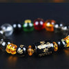 A bracelet made of polished stones in various colors including black, green, red, and amber.