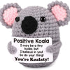 A handmade crochet koala plush toy with pink ears and a card that says You're Koalaty