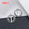 A pair of silver vintage ship anchor charms displayed on a dark surface.