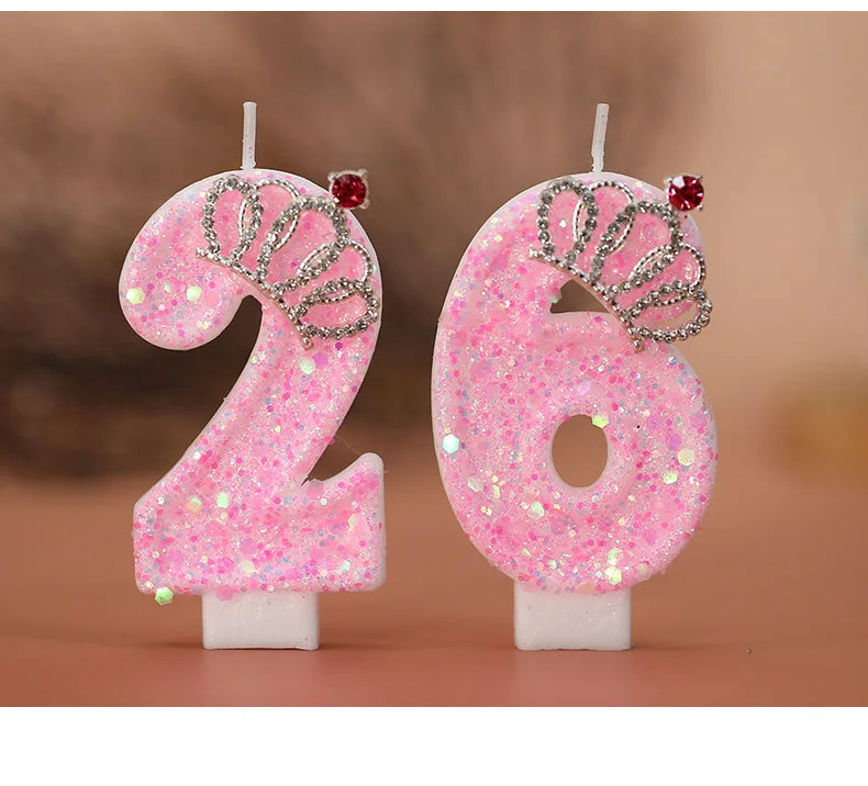 A set of two pink glitter birthday candles shaped like the number 26 with silver crown details