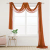 Two panels of orange chiffon fabric draped over a window for wedding decor