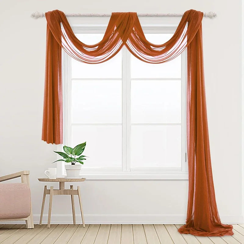 Two panels of orange chiffon fabric draped over a window for wedding decor