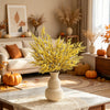 A vase filled with bright yellow artificial silk lover grass on a marble table in a bright living room setting.