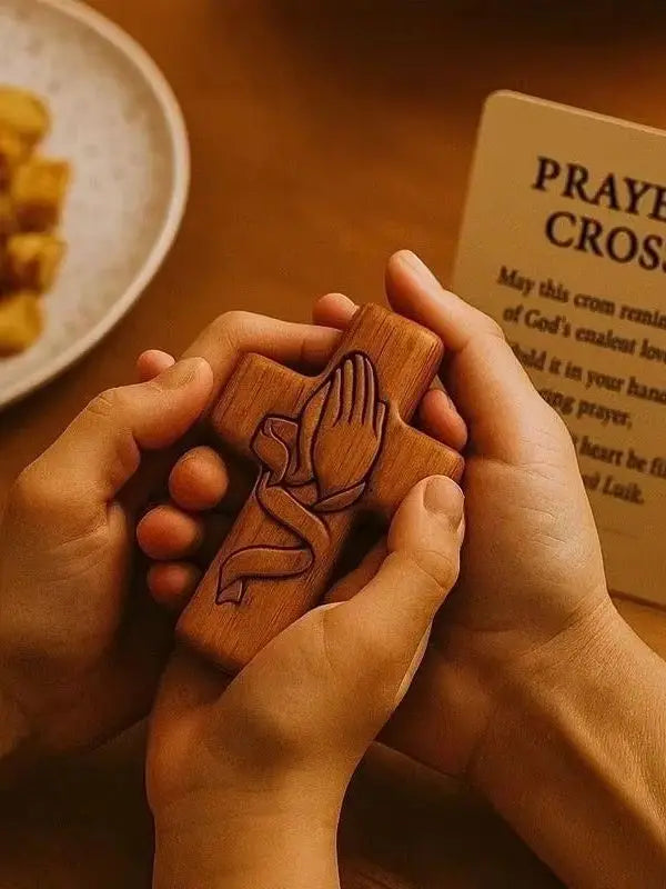 A pair of hands holds a handcrafted wooden prayer cross against a blurred background.