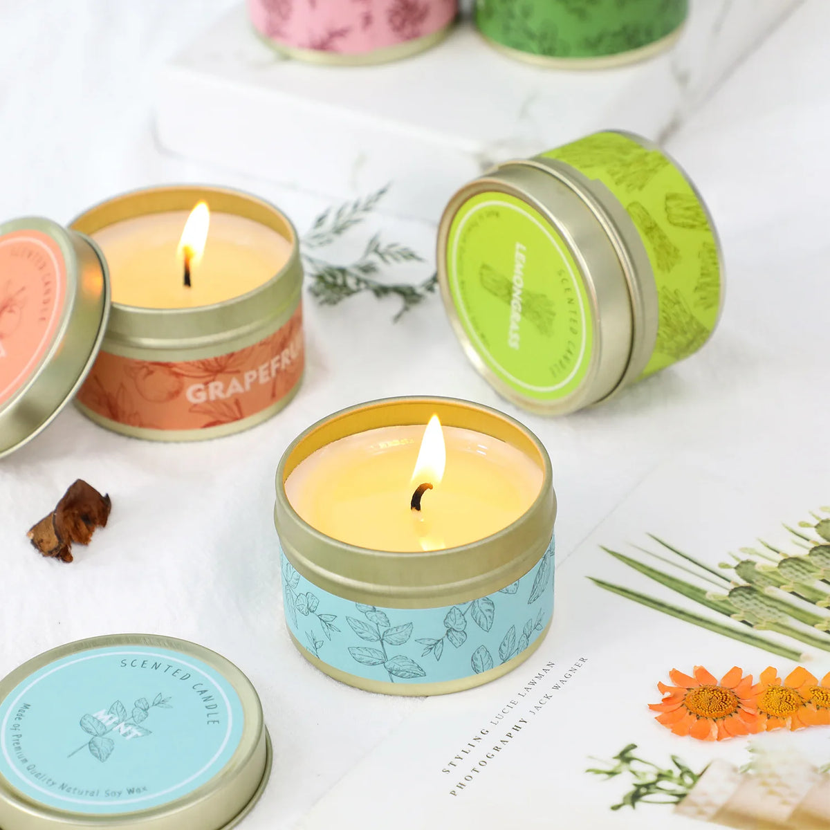 A collection of natural soy wax travel candles in various colors, including orange, green, and blue, set against a white back