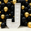 A large white marquee letter L made of balloons is displayed against a dark background.