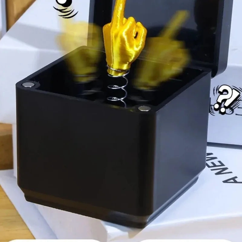 Une boîte cadeau noire avec un geste de main doré, suggérant une farce amusante.