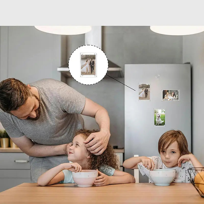 A father gently touches his daughter's face while they look at photos on a refrigerator door.