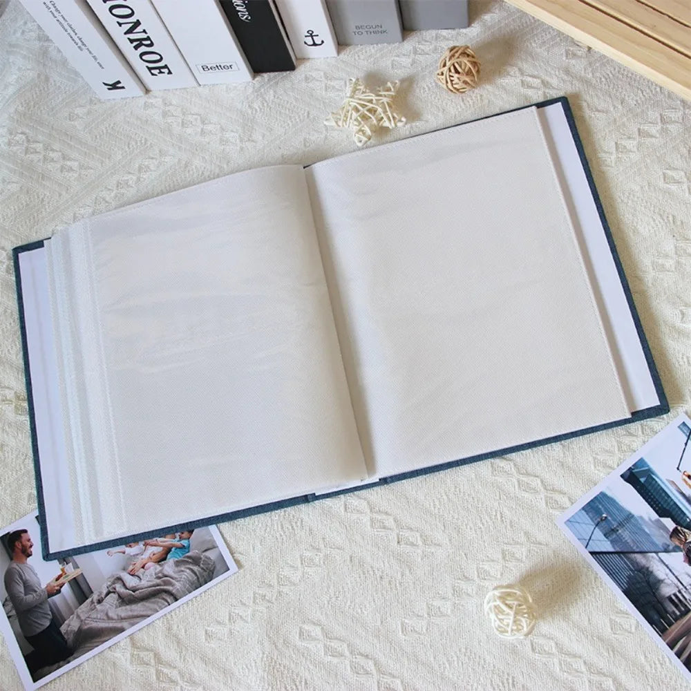 An open linen cover photo album displaying blank pages and decorative twine on a white textured surface.
