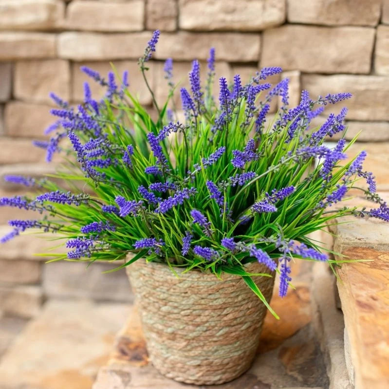A potted artificial lavender plant with purple flowers sits on a stone surface.