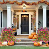 A front porch decorated with autumn foliage and pumpkins, featuring a black door and white columns.