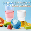 A stack of colorful spherical ice molds, including blue and clear ice balls, next to citrus fruits.