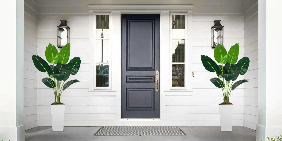 Artificial Bird of Paradise plant in a white planter displayed on a porch with decorative lanterns.