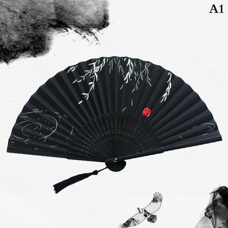 A black hand carved bamboo folding fan with white leaf designs and a small bird detail.