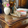 A statue of the Virgin Mary with a rosary holder and Jesus heart on a wooden tray