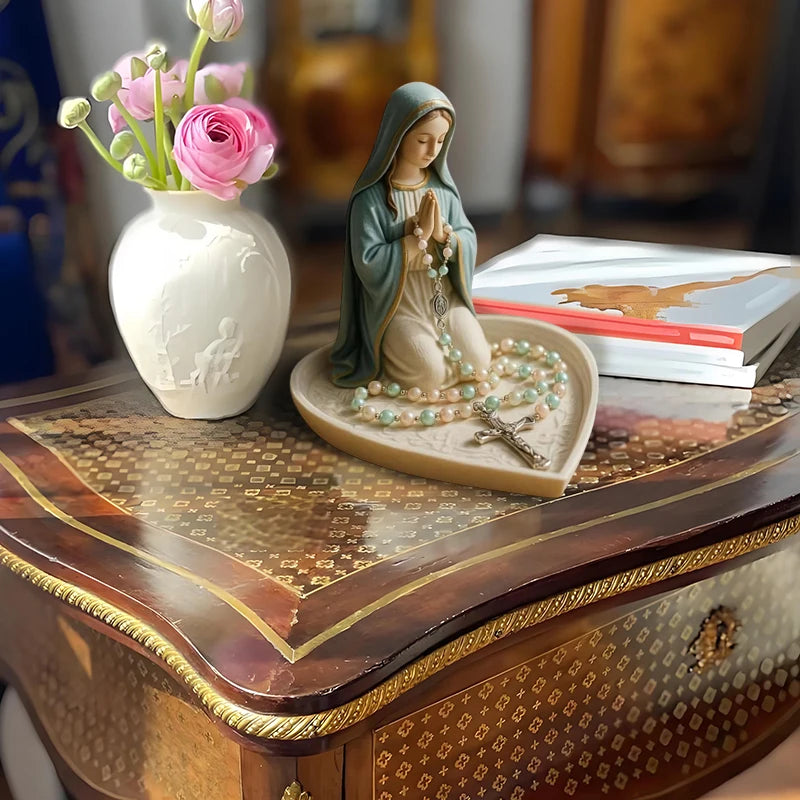 A statue of the Virgin Mary with a rosary holder and Jesus heart on a wooden tray