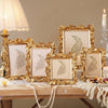 A collection of golden 3D resin photo frames with floral accents displayed on a wooden table.