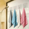 Four folded towels in gray, blue, white, and pink hanging on a wall rack.