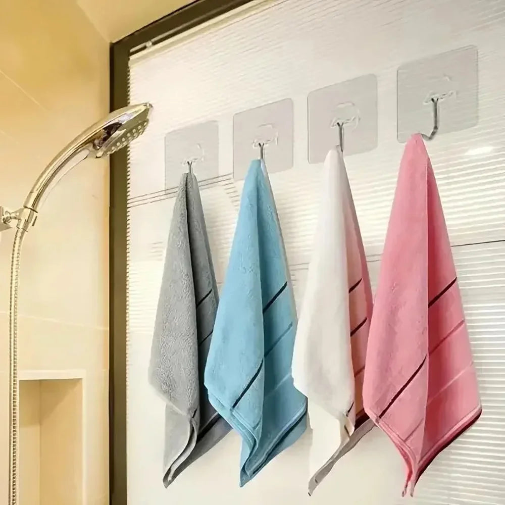 Four folded towels in gray, blue, white, and pink hanging on a wall rack.