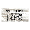 A rustic wooden hanging sign with the text Welcome to our home written in black script on a weathered gray background.