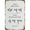 A rustic metal tin sign with black script text that reads The drinks are on us the hangover is on you cheers