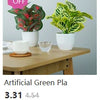 Plante verte artificielle dans un pot blanc, exposée sur une surface en bois avec une étiquette de réduction.