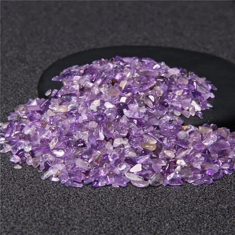 Una pila de piedras de cuarzo amatista púrpura pulidas sobre una superficie gris oscura.