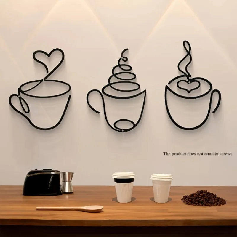 A set of three black iron wall art pieces shaped like coffee cups with hearts, displayed on a wooden table.