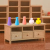 A collection of five miniature resin vases in purple, blue, pink, white, and yellow displayed on a wooden shelf.
