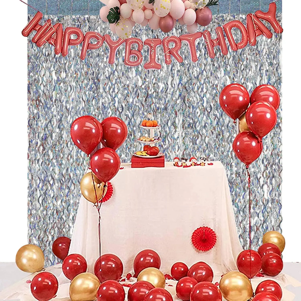 Geburtstags-Hintergrund mit roten und rosa Ballons, Glitzervorhängen und einem Obsttisch.