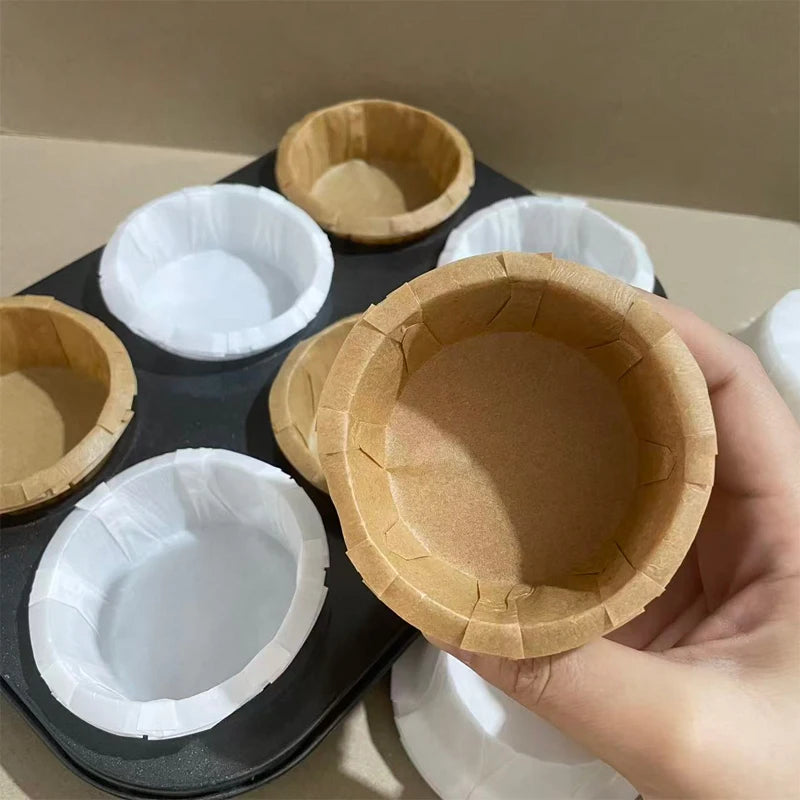 A hand holds a fluted paper cup for baking or party decor, surrounded by other similar cups.